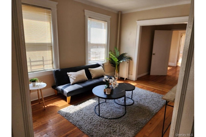 Living room with wood-type flooring and radiator heating unit