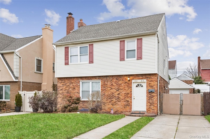 Colonial house with a gate, brick siding, and roof with shingles.