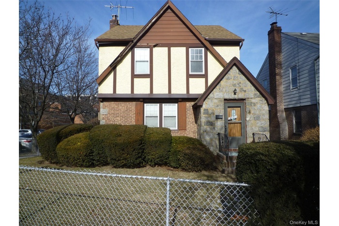 English style home featuring a chimney, stucco siding, stone siding, and brick siding