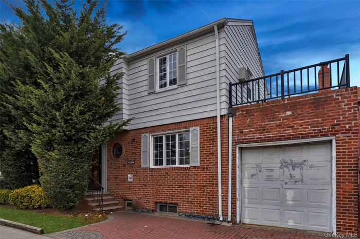 View of front of house featuring brick siding, a patio area, and an attached garage