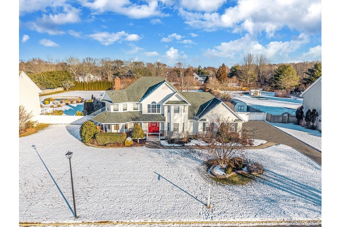 View of front of home featuring driveway, a chimney, and view of wooded area