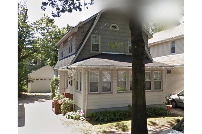 View of front of property featuring a sunroom, an outbuilding, and a garage