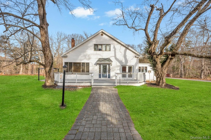 View of front facade featuring a front yard, a chimney, and a wooden deck