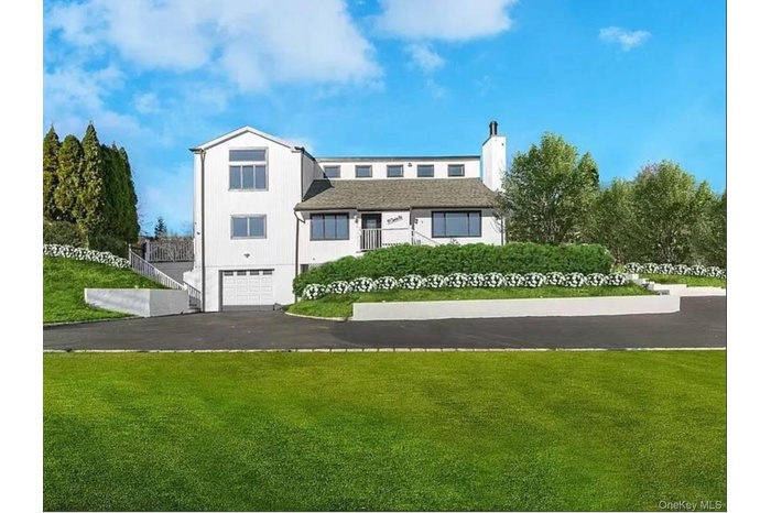 View of front of home featuring a garage, a front yard, driveway, and a chimney
