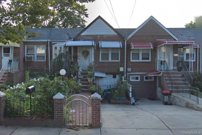 View of front of property with a gate, a fenced front yard, and brick siding