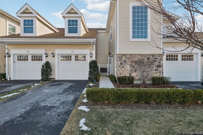 View of front of property with asphalt driveway, stone siding, and a shingled roof