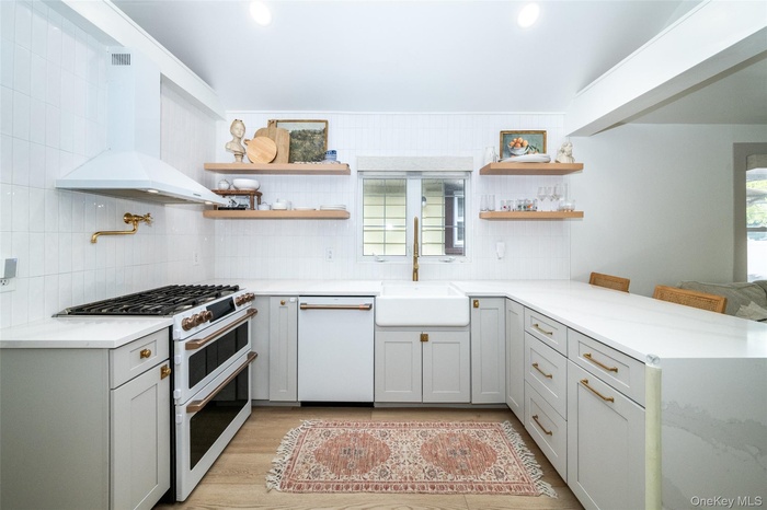 Kitchen with white appliances, open shelves, a peninsula, gray cabinetry, and light stone countertops
