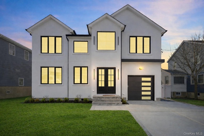 Contemporary home with a lawn, driveway, stucco siding, and an attached garage