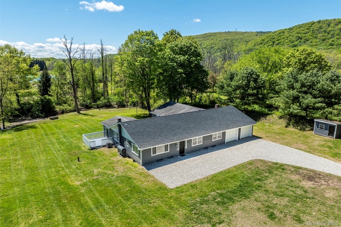 View from above of property with a heavily wooded area and mountains