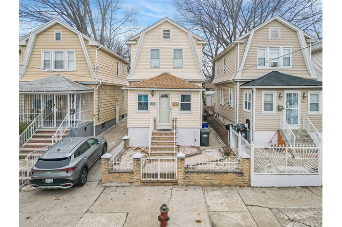 Colonial inspired home featuring a gambrel roof, a gate, a fenced front yard, and a shingled roof