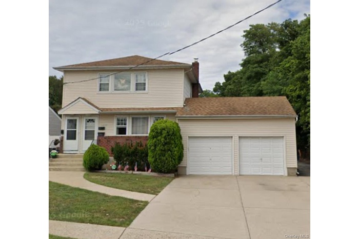 View of front facade featuring concrete driveway, an attached garage, and a front lawn