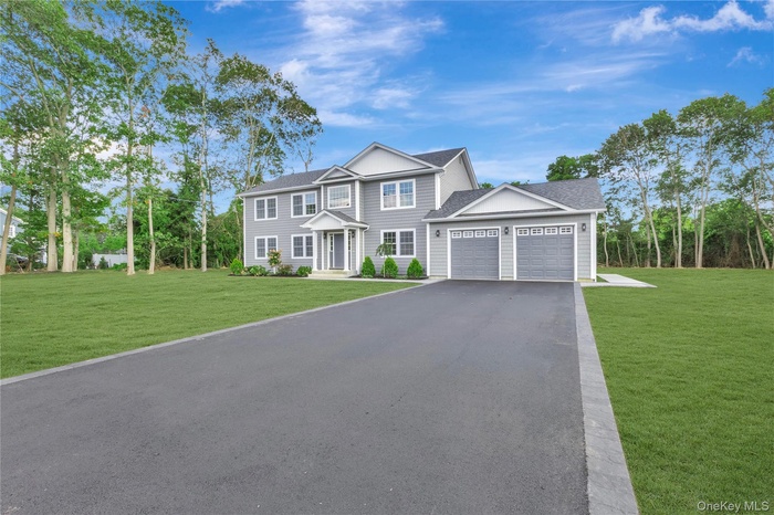 View of front of home with a front yard, driveway, an attached garage, and a shingled roof