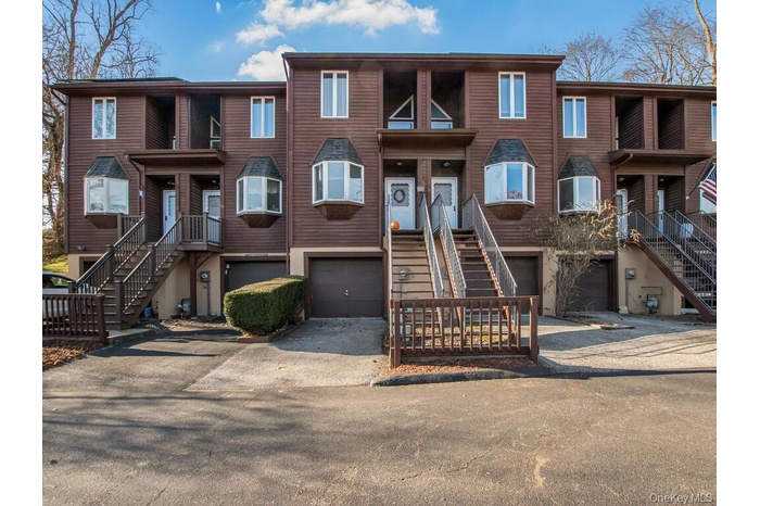 View of front of house with driveway, a garage, and stairway