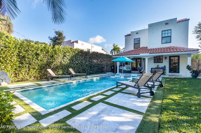 Backyard oasis with heated salt-water pool, covered loggia, stone pavers, lush landscaping, synthetic turf, & impressive surround sound