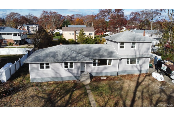 Back of property featuring a residential view, a shingled roof, and view of wooded area