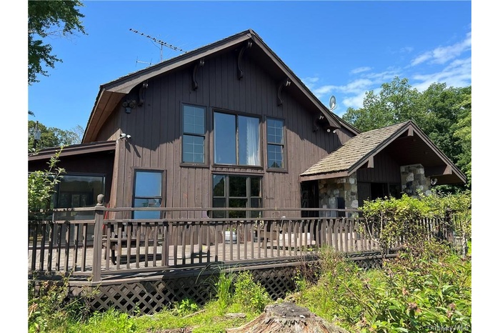 Rear view of property with a deck and a sunroom