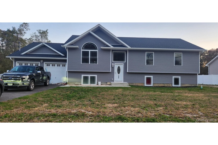 Raised ranch featuring asphalt driveway, an attached garage, and entry steps