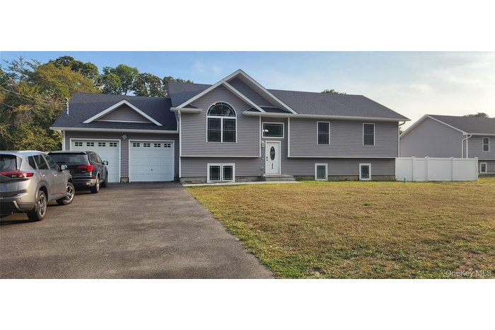 Bi-level home with asphalt driveway, a garage, and a shingled roof