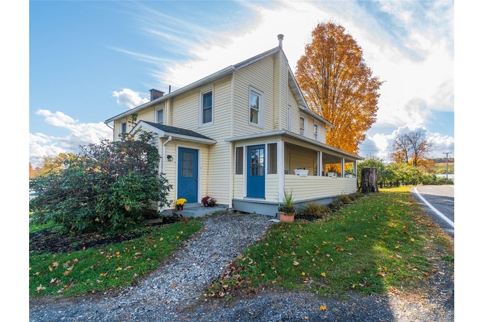 View of front of property with a chimney, a front yard, and a porch