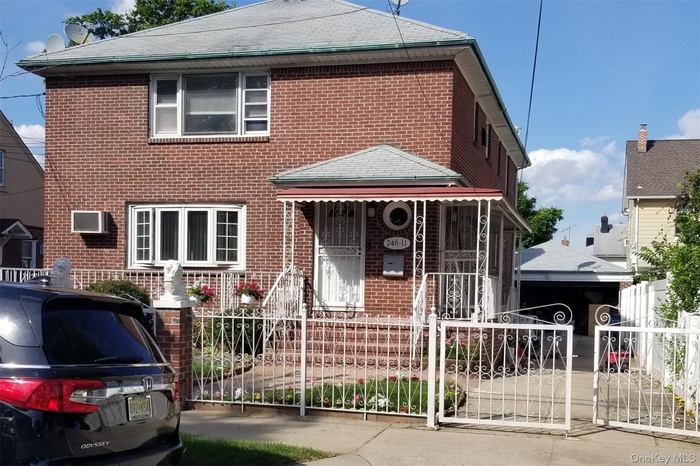 Traditional home with brick siding, a fenced front yard, covered porch, and a gate