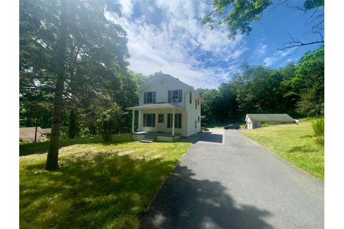 View of front of home featuring asphalt driveway and a front yard