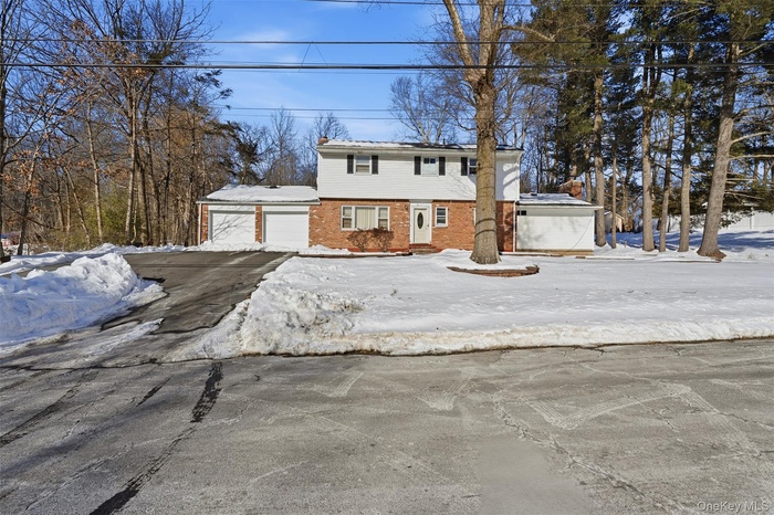 Colonial home featuring a garage and brick siding