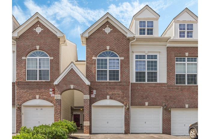 Traditional-style house with an attached garage, brick siding, and driveway