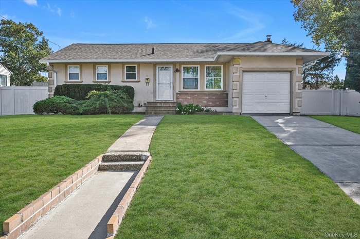 Ranch-style home featuring an attached garage, stucco siding, driveway, and roof with shingles