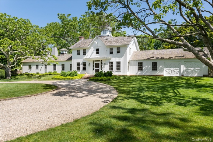 View of front facade with a chimney, a front lawn, and driveway