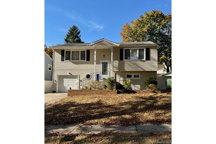 Raised ranch with concrete driveway and an attached garage