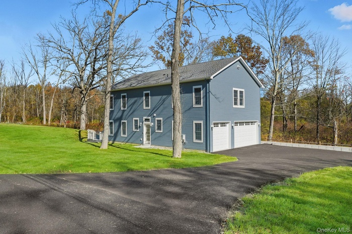 View of side of home featuring a yard, asphalt driveway, and a shingled roof