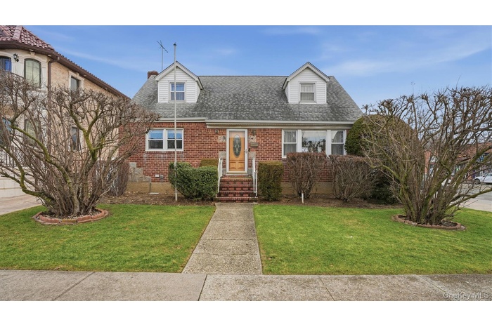 New england style home with a shingled roof, a front lawn, and brick siding