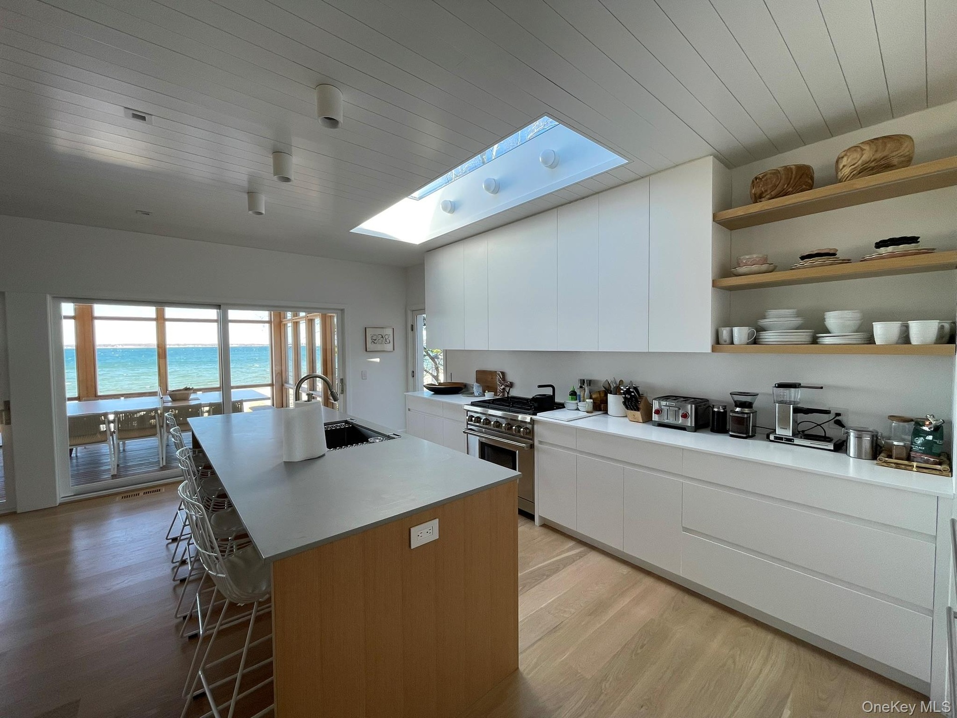 Kitchen with high end stainless steel range, a kitchen breakfast bar, a skylight, a kitchen island with sink, and a sink