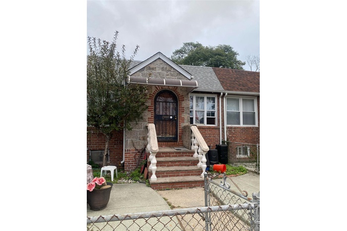 View of front of property featuring a shingled roof, brick siding, a gate, and a fenced front yard