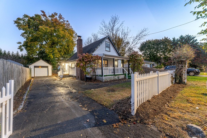 View of front of home with a porch, fence, driveway, and a garage