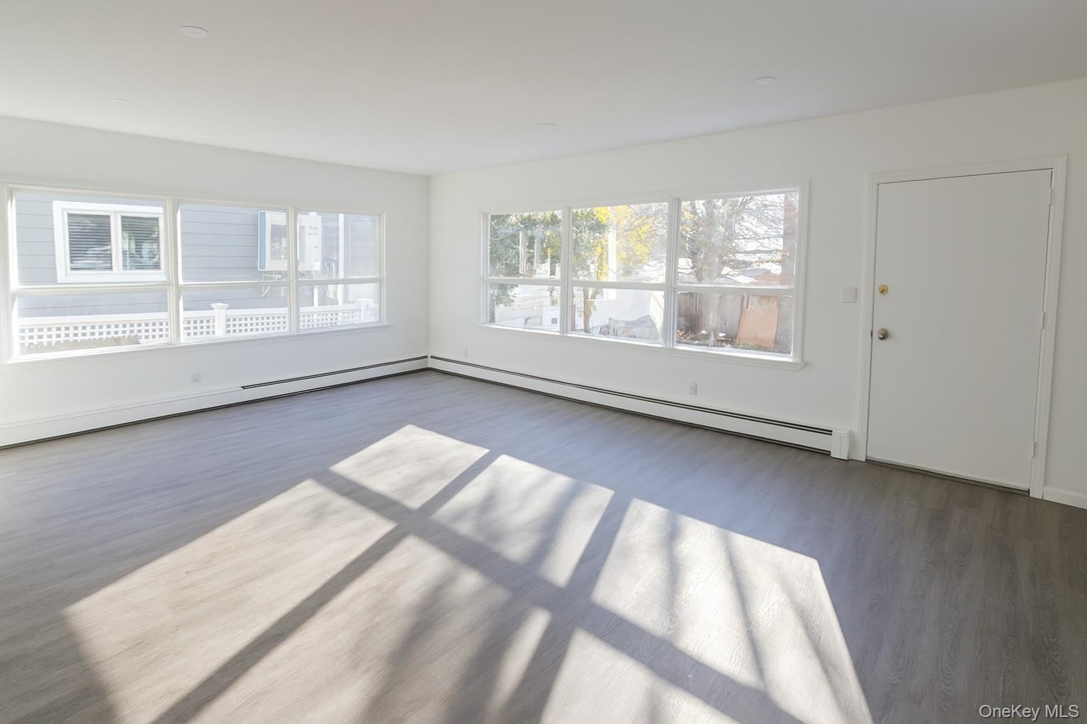 Spare room with baseboard heating and wood finished floors