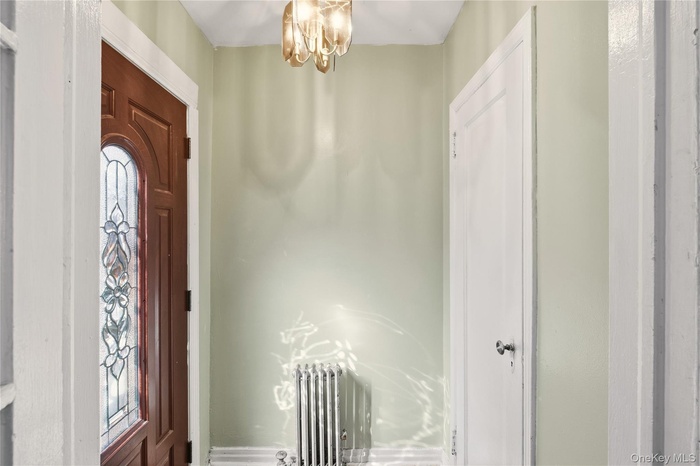 Close up pic of entrance foyer featuring hanging lights, radiator heating unit, and plenty of natural light