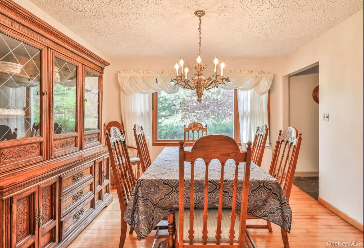 Dining space with light wood-style floors, a chandelier, and a textured ceiling