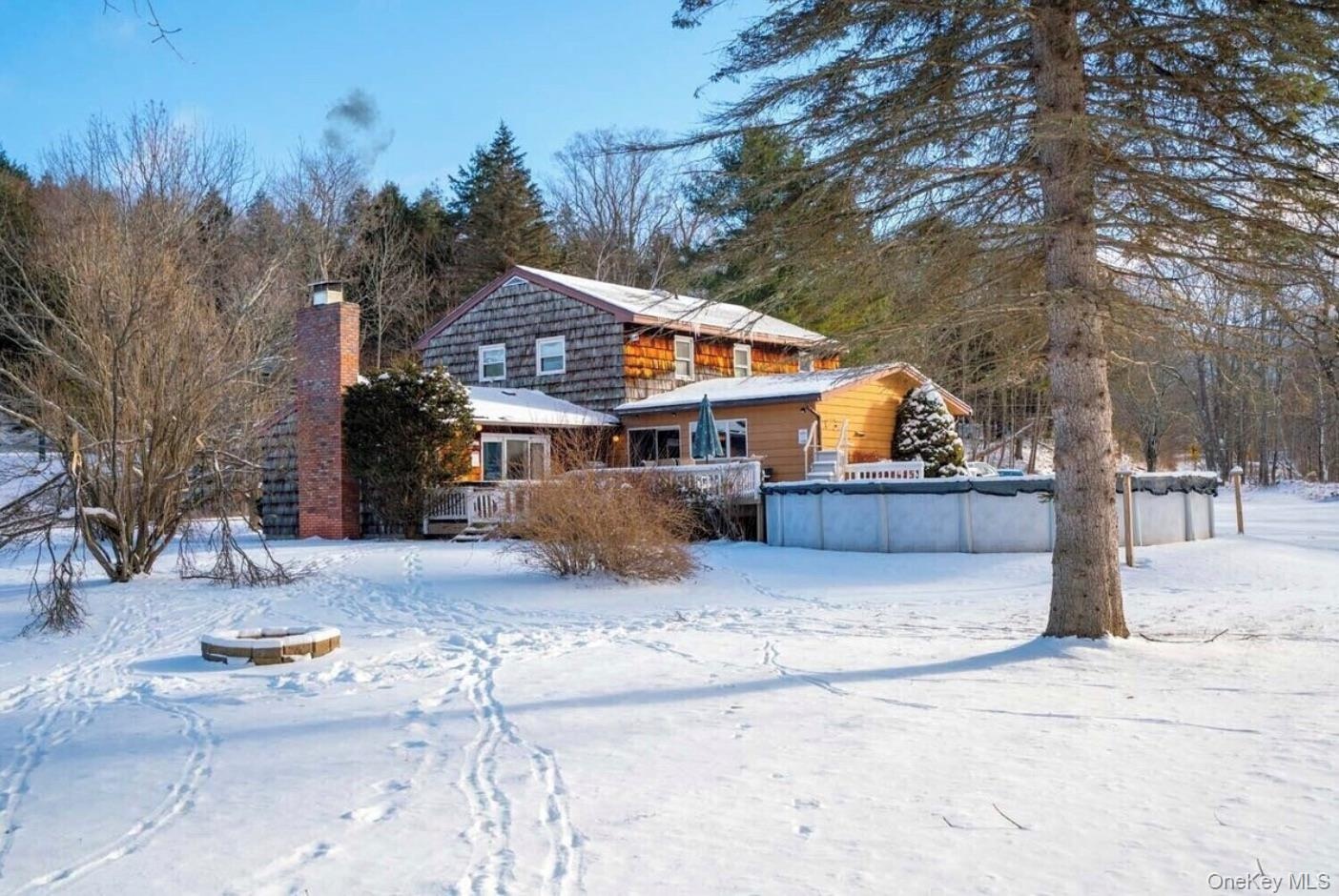 Snow covered rear of property with a chimney