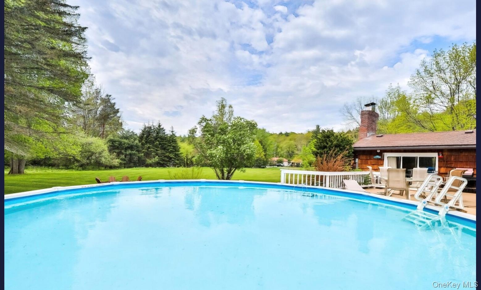 Outdoor pool with a patio and a lawn