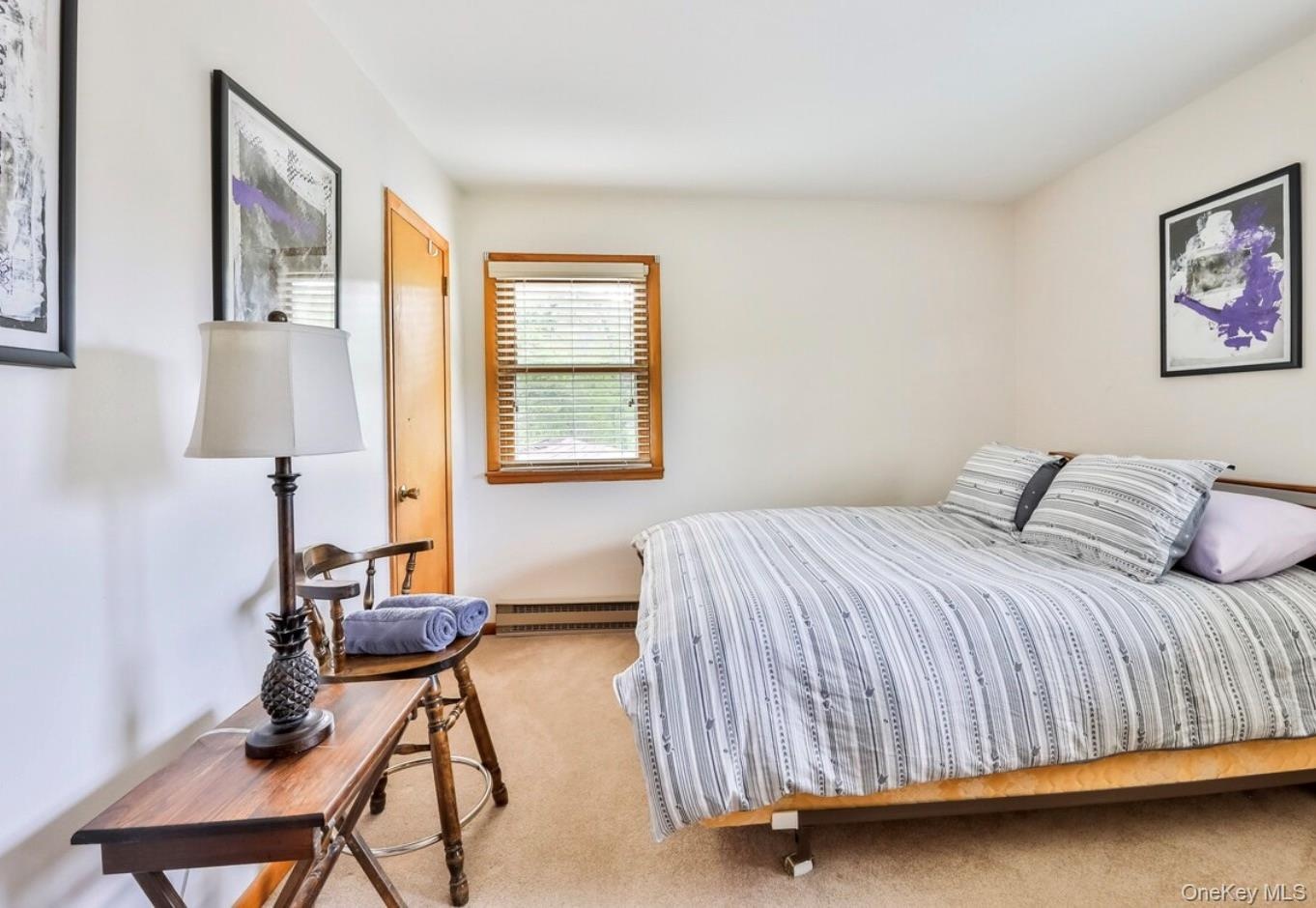 Bedroom featuring light carpet and baseboard heating