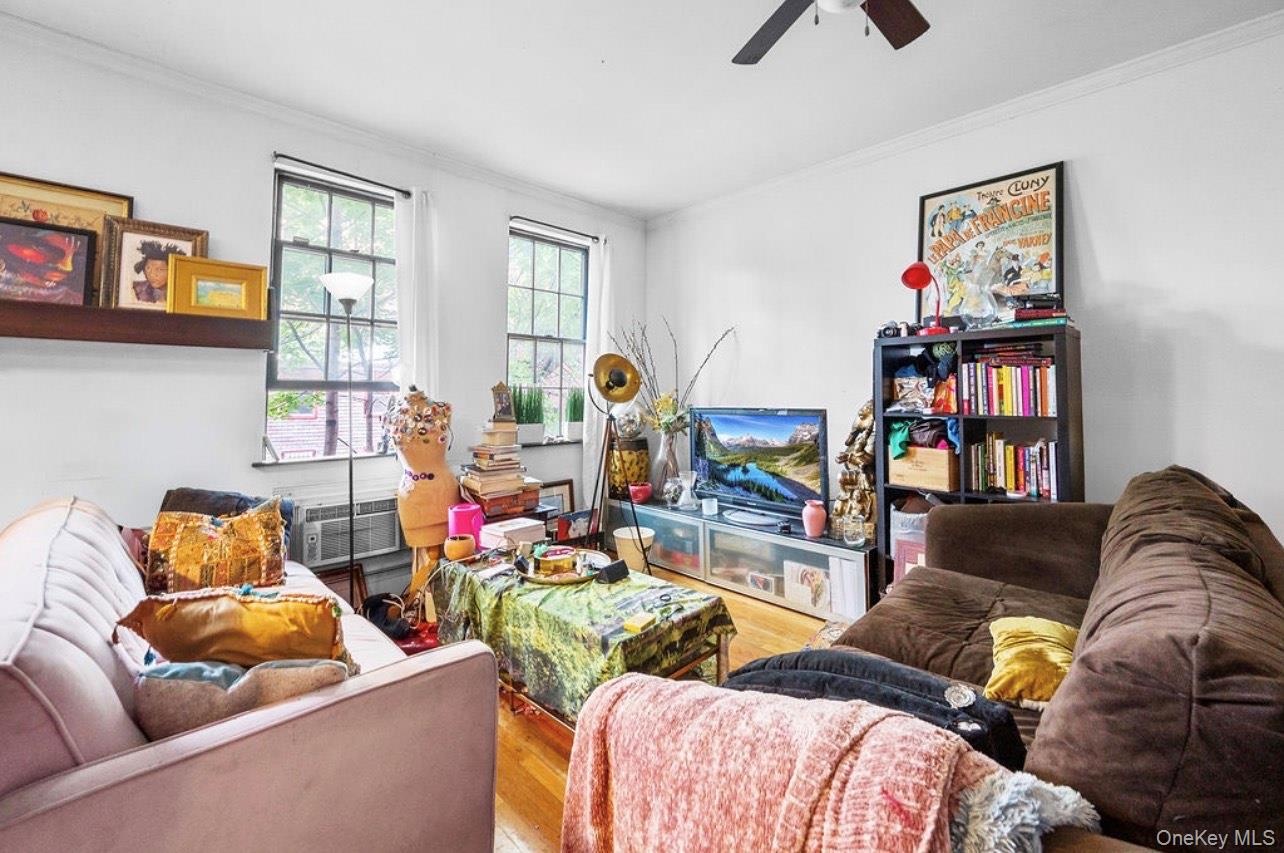 Living room featuring crown molding, wood finished floors, and a ceiling fan