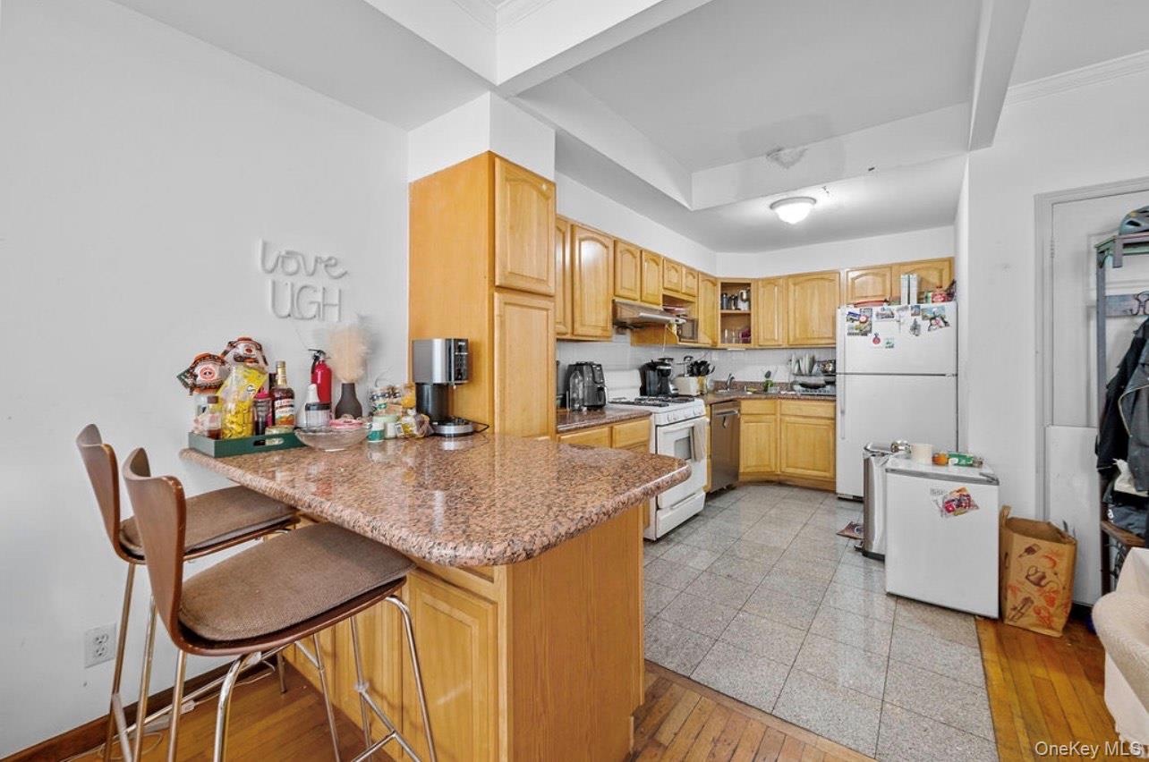 Kitchen with a kitchen breakfast bar, open shelves, light wood-style floors, white appliances, and a peninsula