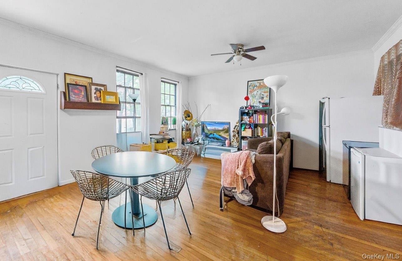 Dining area with hardwood / wood-style floors, crown molding, and ceiling fan
