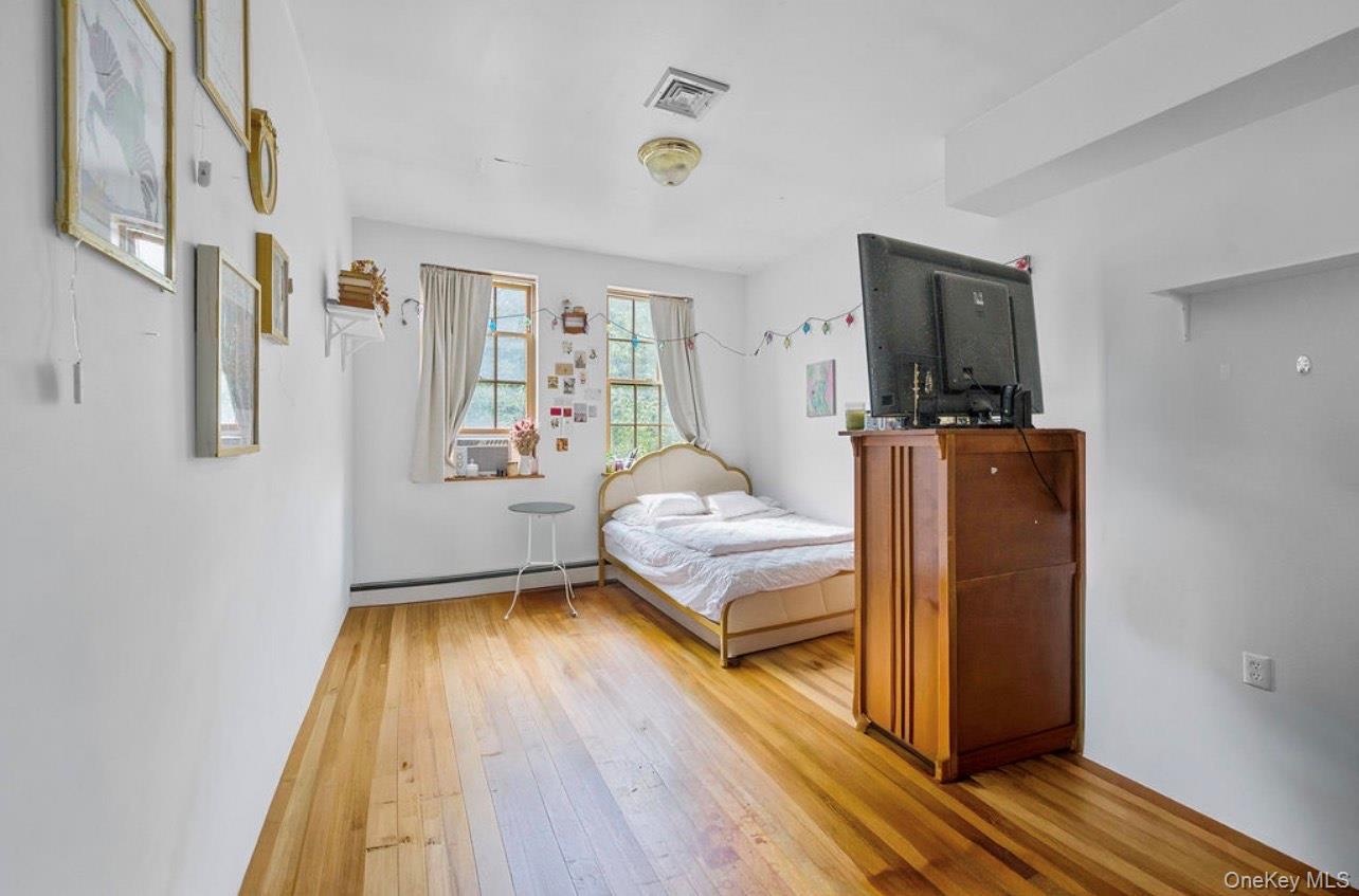Bedroom with light wood-style flooring and a baseboard radiator