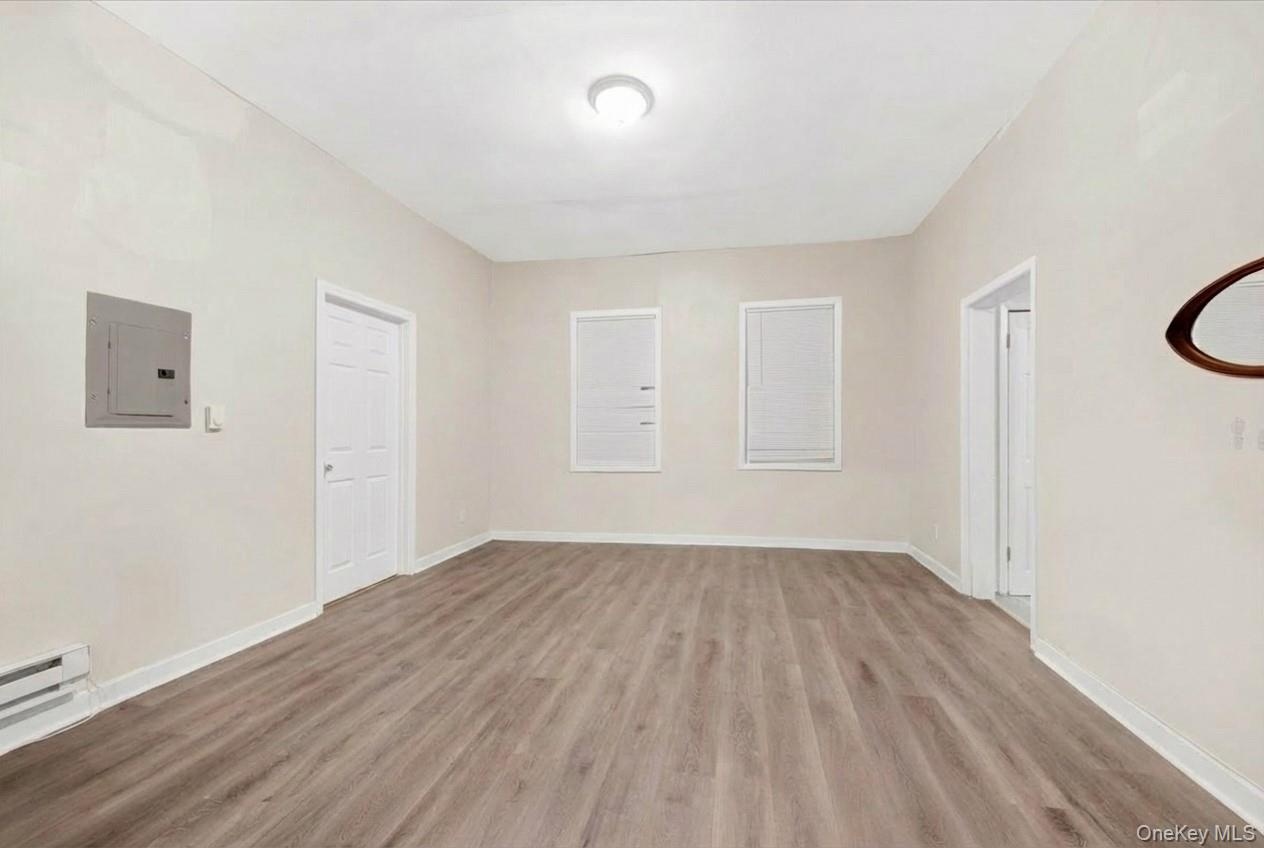Unfurnished room featuring electric panel and light wood finished floors