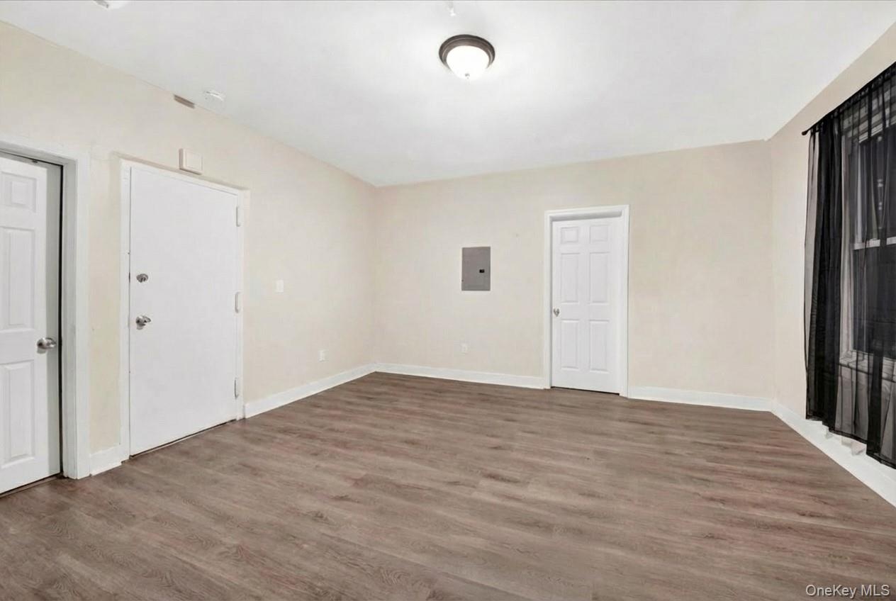 Unfurnished room with wood finished floors and electric panel