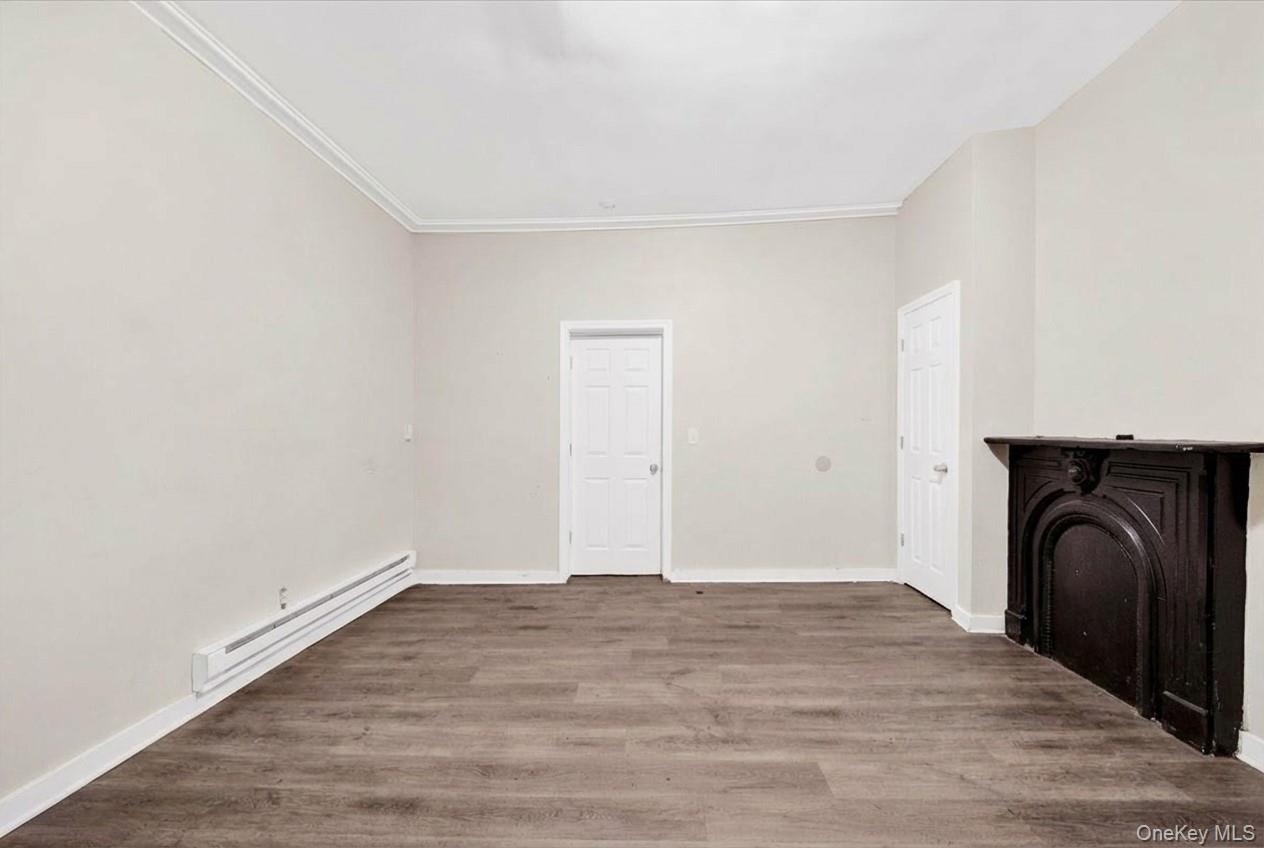 Unfurnished bedroom featuring baseboard heating and wood finished floors