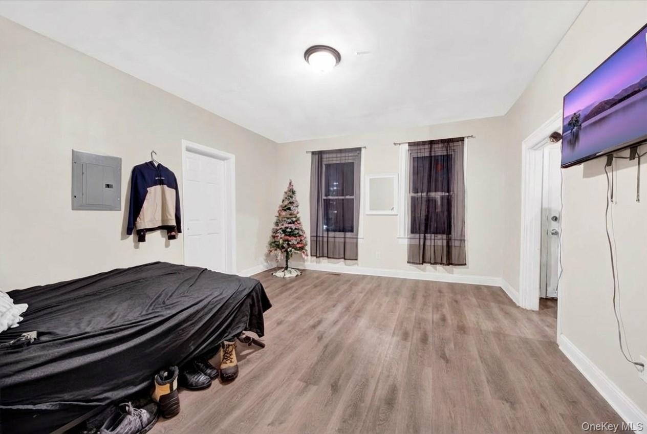 Bedroom with electric panel and light wood finished floors