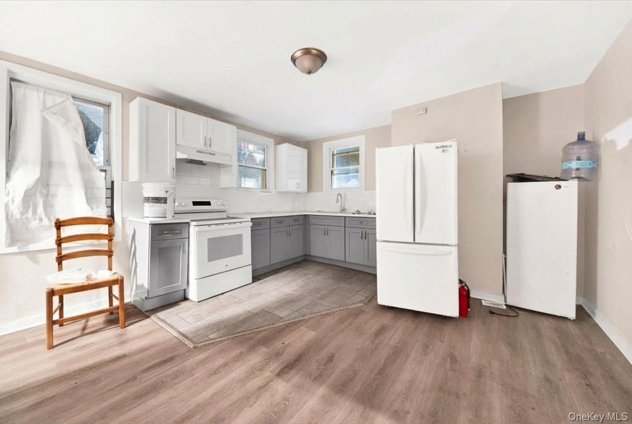 Eat-in Kitchen with gray cabinetry, white appliances, backsplash, light countertops, and white cabinets